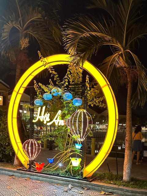       Illuminated sign and lanterns at night, with 'Hoi An' visible.
  