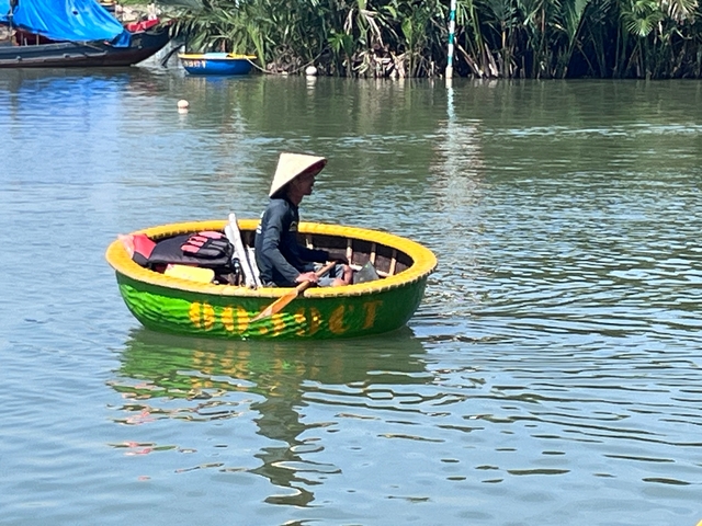A person in a traditional Vietnamese circular boat on a river.