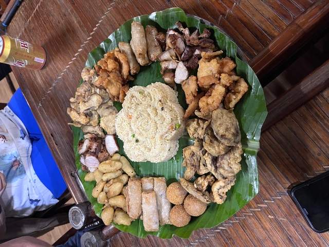       A platter of assorted Vietnamese fried snacks and rice on a large leaf.
  