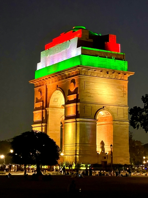       India Gate illuminated with tricolor lights at night.
  