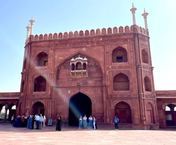Large red sandstone fort entrance with people at the base.