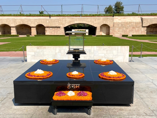 Memorial site with floral wreaths and a glass case.
