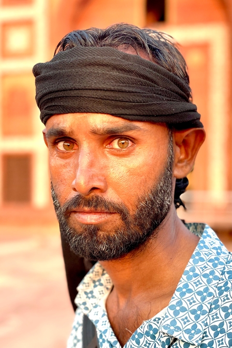       Portrait of a man with intense expression and a background of historical architecture.
  