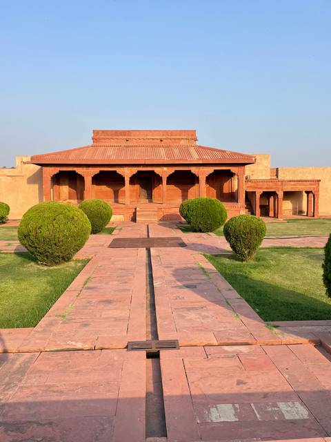       Garden courtyard leading to a historical building with arched entrances.
  