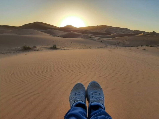 A person's feet in the foreground of a desert sunset