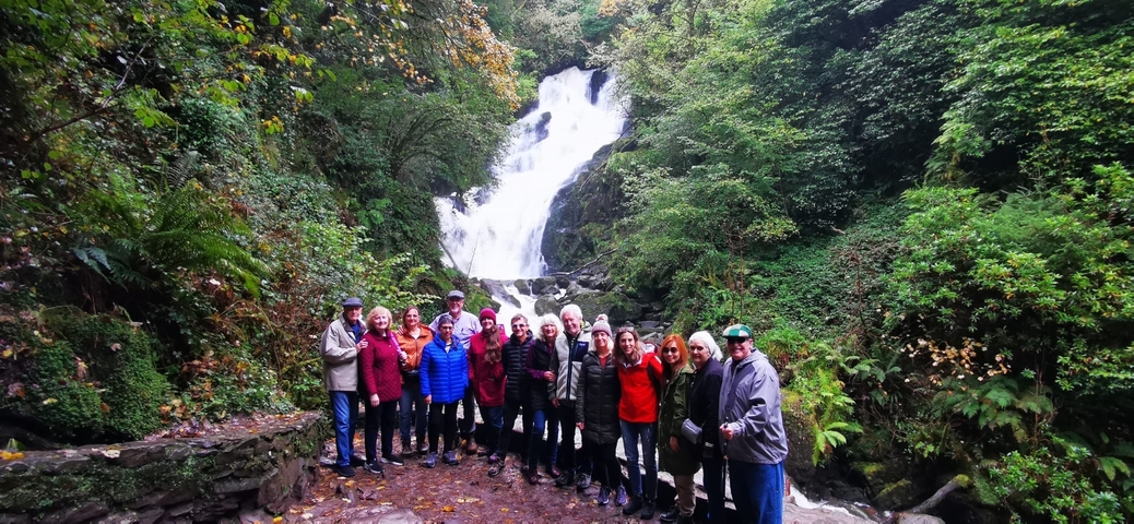 Large group posing in front of a waterfall in a forest