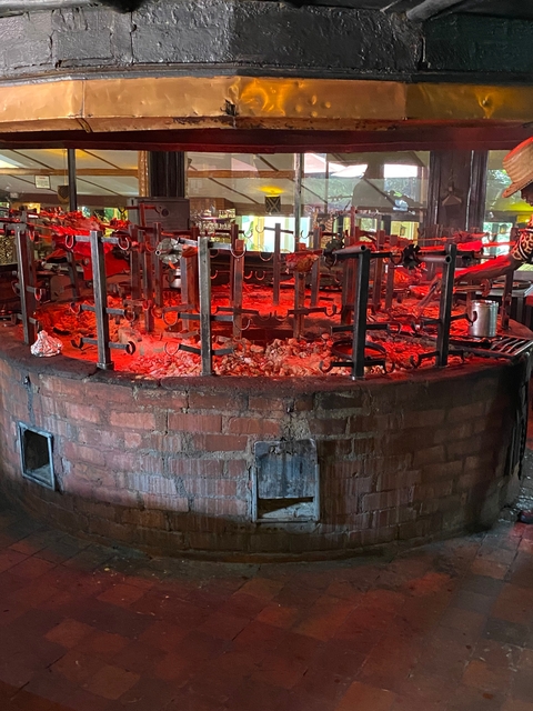       Large circular grill with meat being cooked.
  