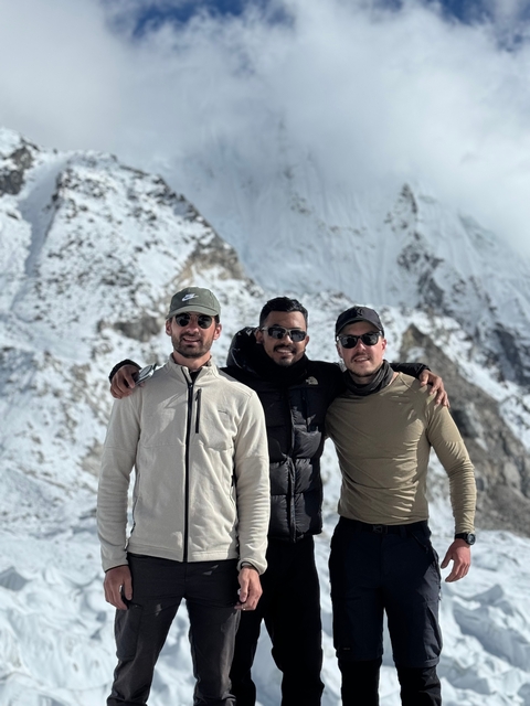 Three friends posing with a snowy mountain backdrop.
