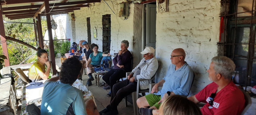       Group of people sitting on a porch during a meal.
  
