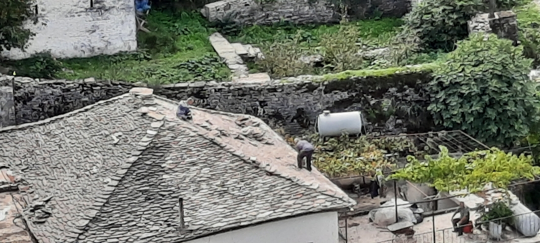       People working on a rooftop in a rustic setting.
  