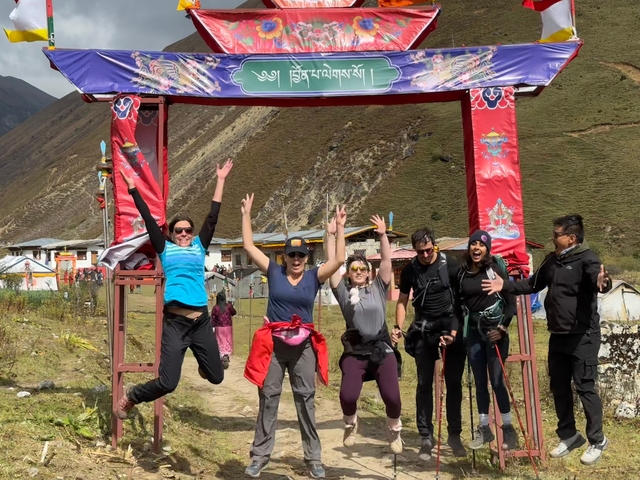 Group of people jumping in front of a decorated archway.