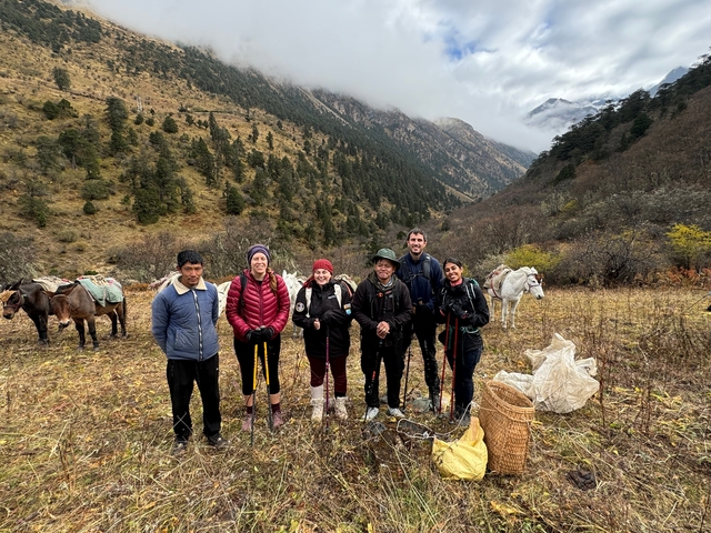 Group of hikers posing with animals in a mountainous landscape.
