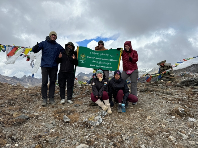 Group posing with a national park sign at a summit.
