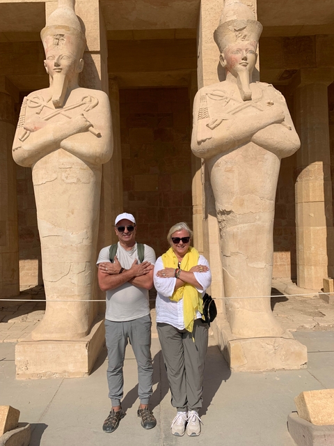 Two people posing with ancient statues.