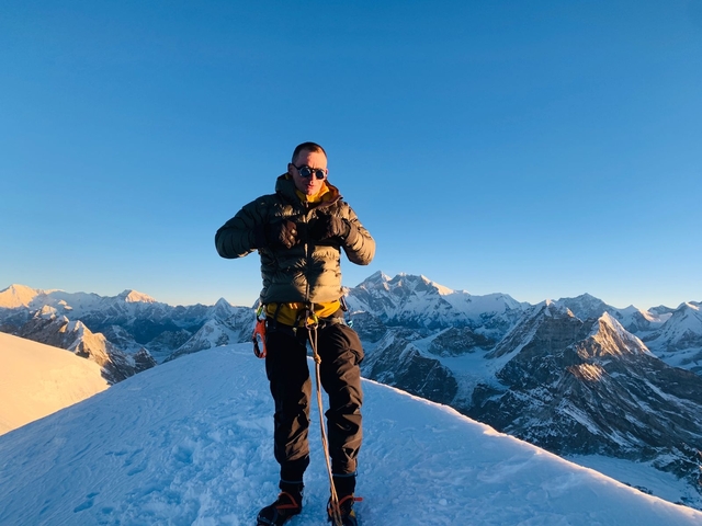       Person climbing a snowy mountain with panoramic views.
  