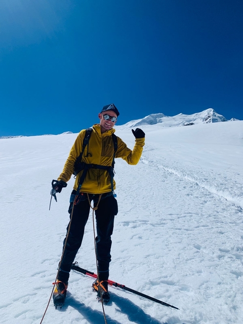       Person smiling on a snow-covered trail with a bright sky.
  