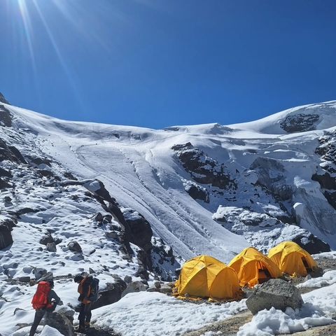       Snow-covered mountains with tents in the foreground.
  