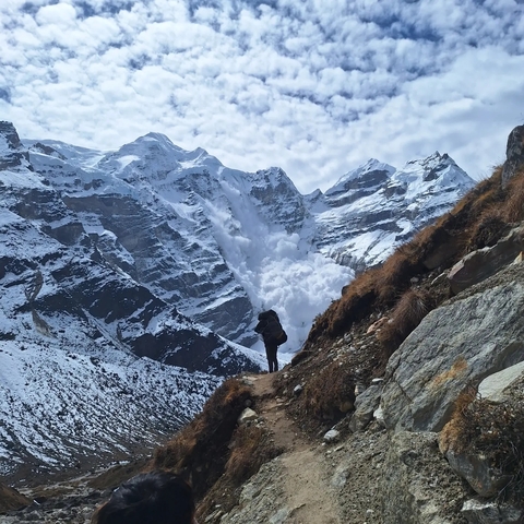       Hiker in a snowy mountain landscape with snow avalanche.
  