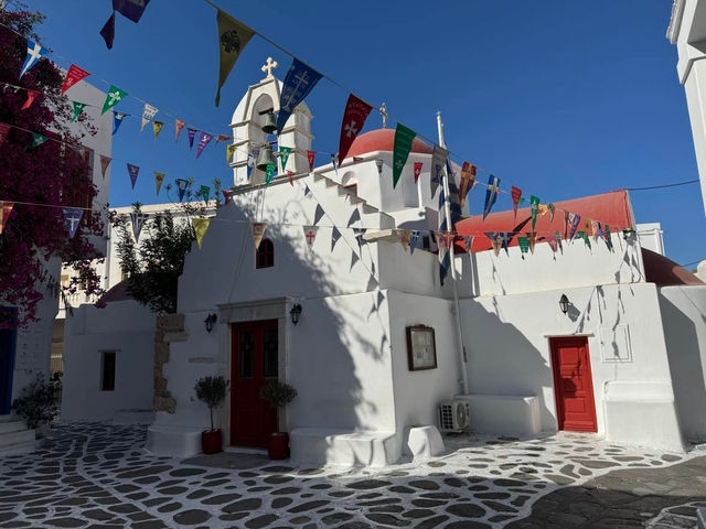       White church with red domes and flags in a village
  