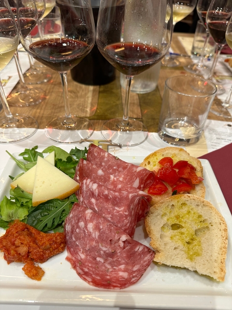 Plate of meats, cheese, and vegetables with wine glasses.