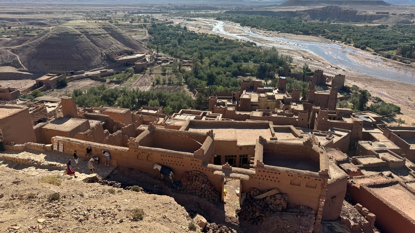       Traditional Moroccan village seen from above with river and green fields.
  