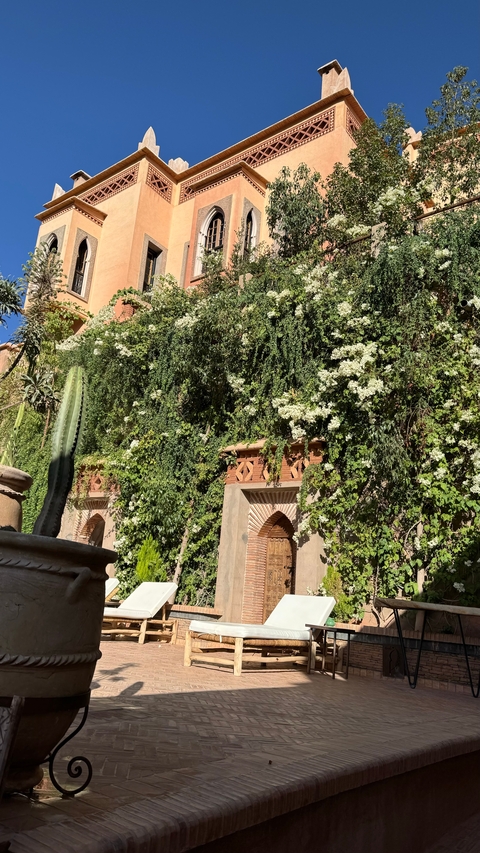       Building facade covered with green vines and flowers.
  
