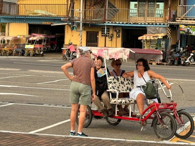 Group of people resting on a rickshaw in a street.