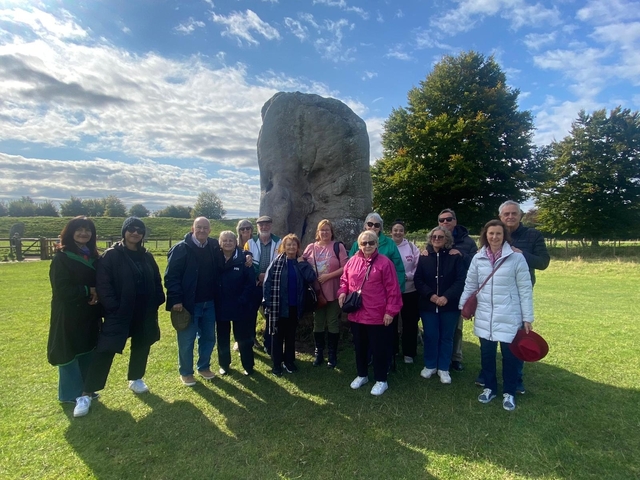       A group of people posing in front of a large stone monument.
  