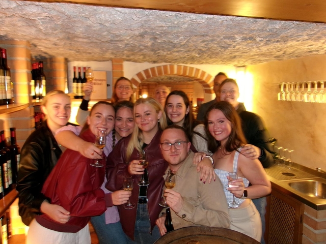Group of friends holding glasses in a wine cellar.