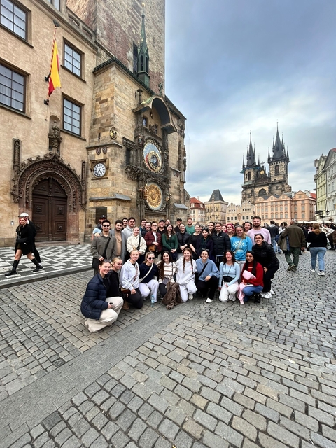 Group of tourists posing in front of the Astronomical Clock in Prague.