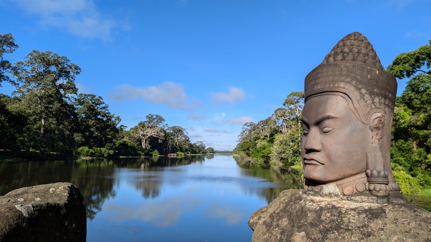 Stone statue overlooking a river surrounded by lush forest.