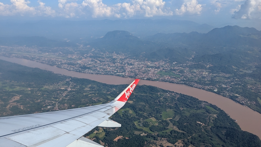       View from an airplane window showing a wing and landscape below.
  