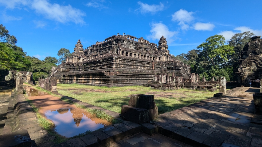       Ancient stone temple surrounded by lush greenery and clear blue skies.
  