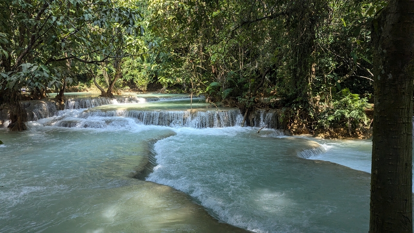      Serene water cascading over terraced rocks amidst greenery.
  