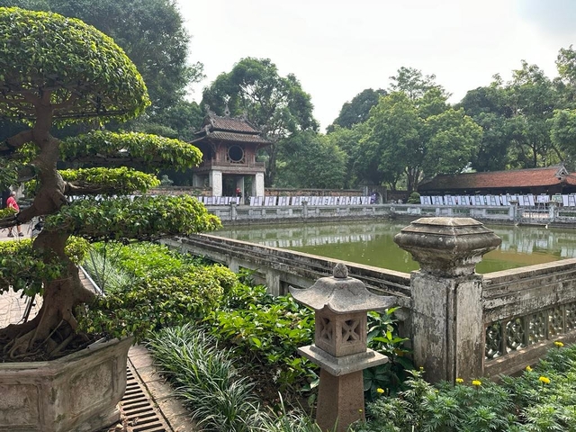 Pagoda and courtyard with a small pond and framed photos displayed.
