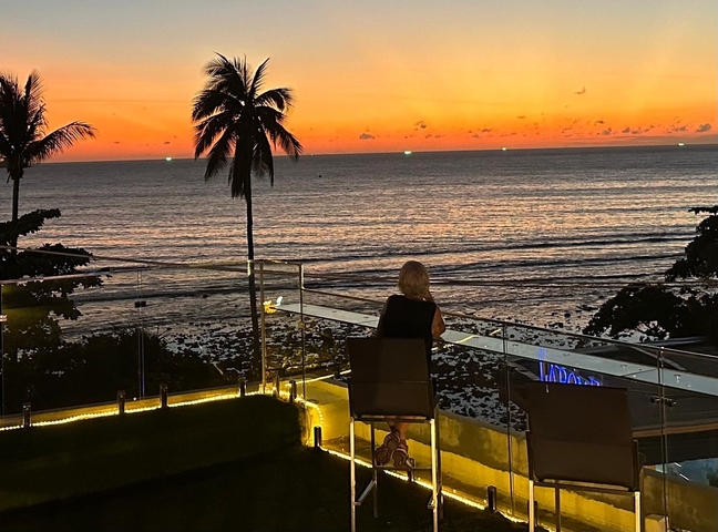 Person sitting and watching the sunset over the ocean.