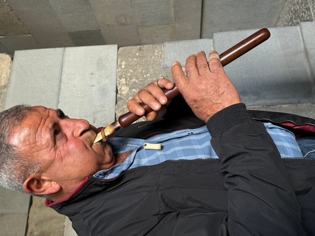 Man playing a musical instrument outdoors.