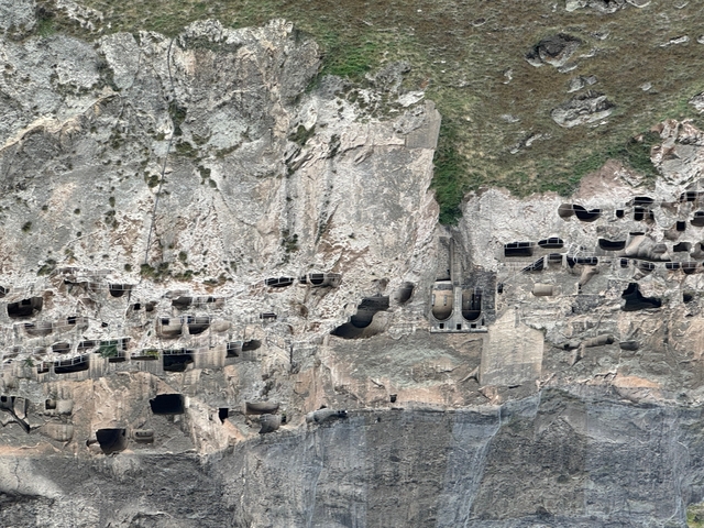 Rocky cliff with numerous cave dwellings.