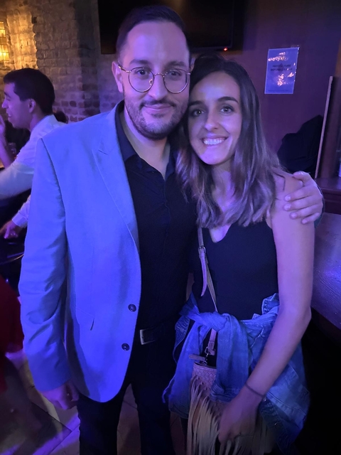 Couple posing together at an event under purple lighting.