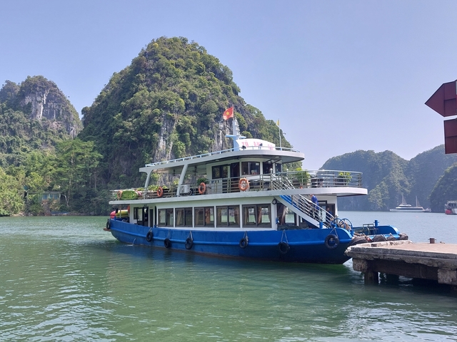 Tourist boat docked in a bay surrounded by limestone mountains.