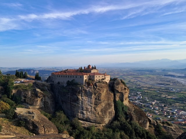 Monastery perched on a rock with landscape view.