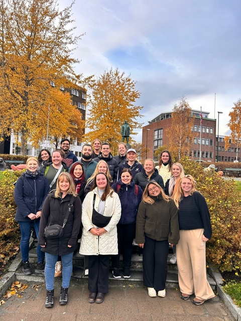       Group of people standing outdoors with autumn foliage.
  