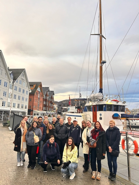       Group photo in front of boats and buildings.
  