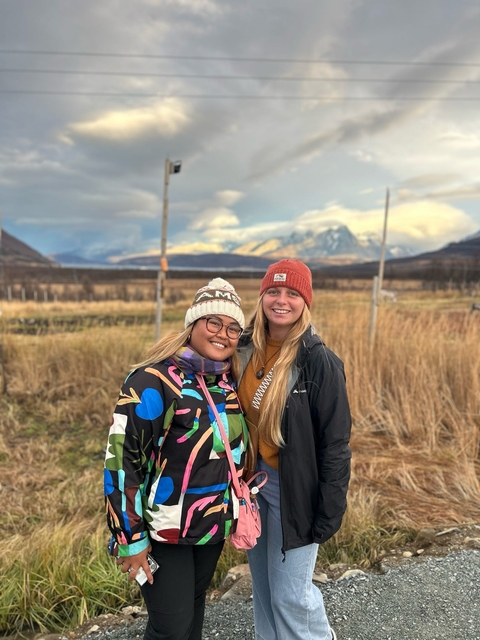       Two people in winter clothing with snowy mountain background.
  
