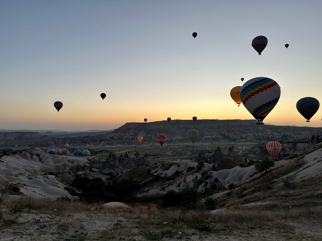       Hot air balloons over a valley during sunrise.
  
