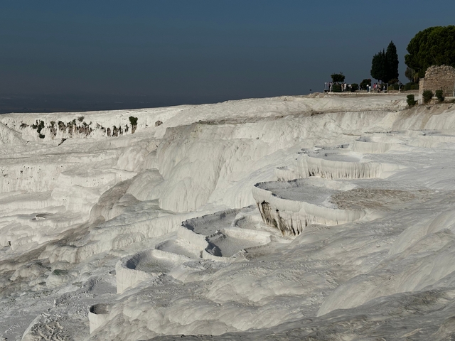 White travertine terraces at a natural site with people exploring.