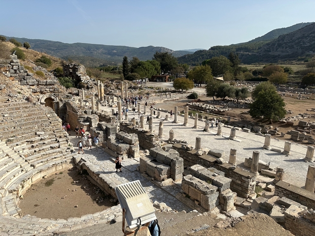       Visitors exploring ancient ruins and columns at an archaeological site.
  