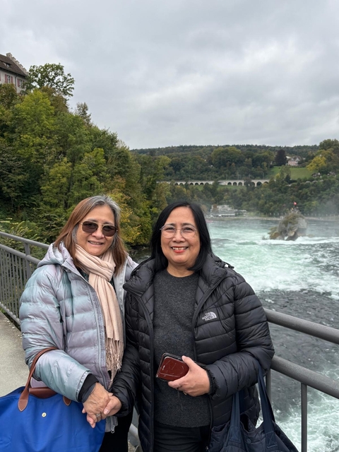       Two people on a bridge with a river in the background.
  