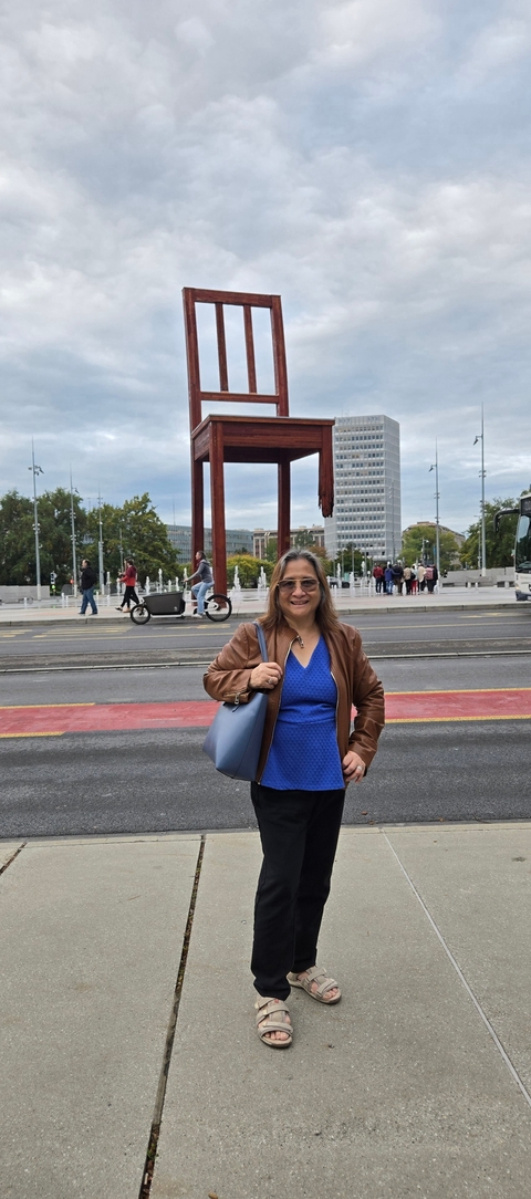 Person posing in front of a large sculpture in a city setting.