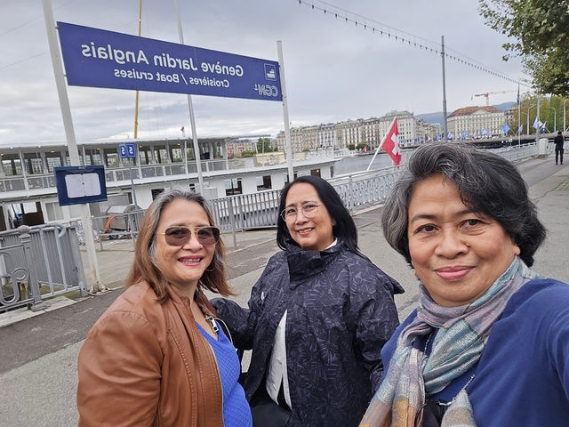 Three people posing by a dock with a cityscape in the background.